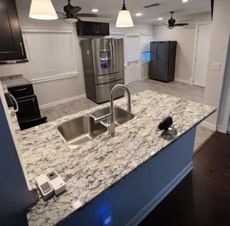 Modern kitchen with white cabinets, granite countertops, stainless steel sink, and blue island with pendant lights